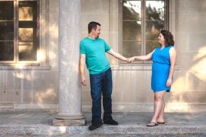 A man and woman are shaking hands in front of a building.