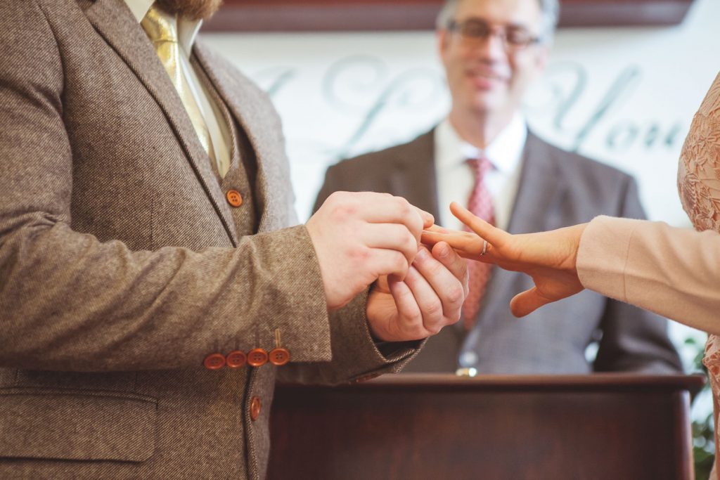 groom sliding a ring on the bride's finger