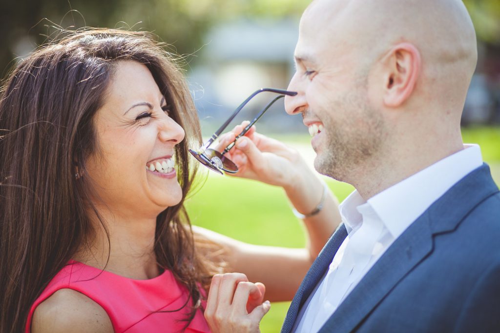 Woman takes sunglasses off her fiance's face.