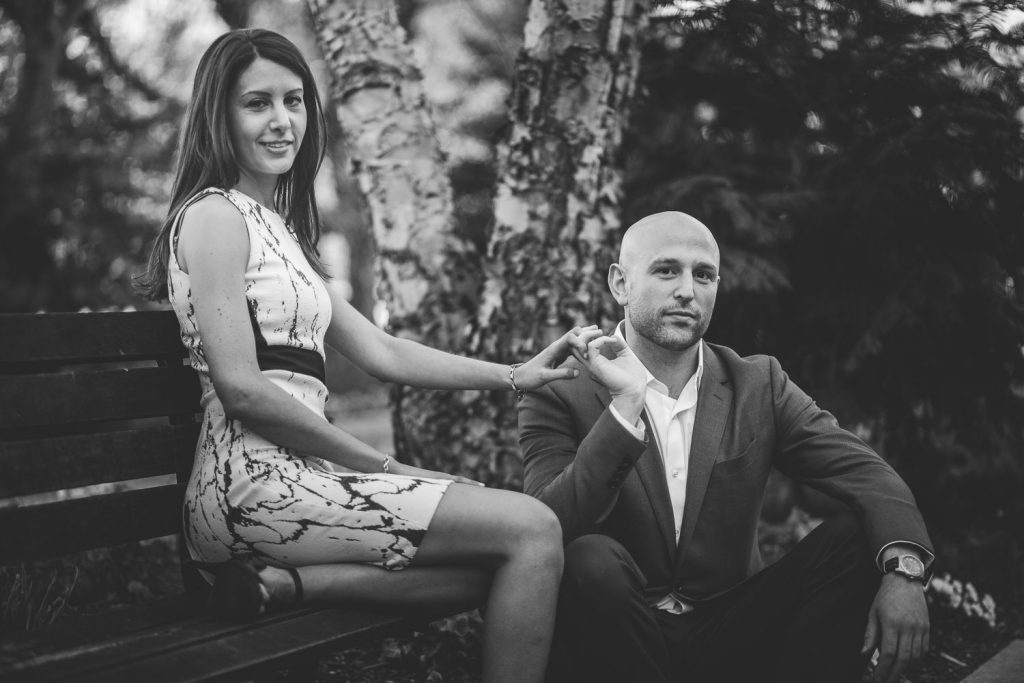 Black and white photo of engaged couple sitting on a bench in DC