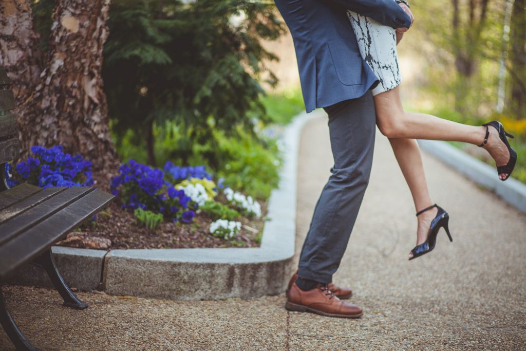 Photo of engaged couple's feet as man lift's his fiancee off the ground.