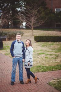 A couple posing for a portrait in front of a downtown Annapolis brick building.