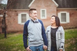 A portrait of an engaged couple standing in front of a brick house in Downtown Annapolis.