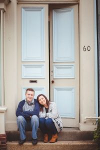 A portrait of a couple sitting on the steps of a blue door in Downtown Annapolis.