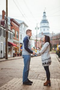 An engaged couple standing on a cobblestone street in Downtown Annapolis.