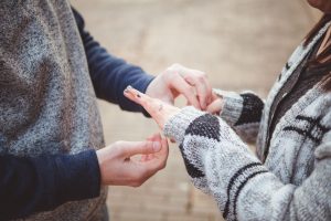 A man is putting a ring on a woman's finger during a romantic marriage proposal in Downtown Annapolis.