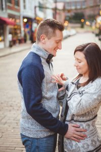 A portrait of an engaged couple on a cobblestone street in Downtown Annapolis, admiring their engagement ring.