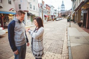 A couple in Downtown Annapolis, looking at each other on a cobblestone street.