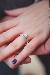 A woman's hand holding a diamond engagement ring during a marriage proposal in downtown Annapolis.