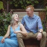 An engaged couple sitting on bricks in a garden for their Downtown Annapolis engagement portrait.