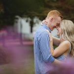 A couple embraces in front of purple flowers during their engagement session in Downtown Annapolis.