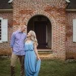 An engaged couple having their portrait taken in front of a brick house in downtown Annapolis.