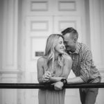 A black and white portrait of an engaged couple leaning against a railing in Downtown Annapolis.