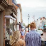 A couple walking down a downtown city street holding hands.