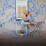 A beautiful portrait of a man and woman sitting on a bicycle in downtown Annapolis, with a mural as the backdrop.