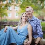 An engaged couple posing for a portrait on a bench in Downtown Annapolis park.