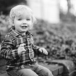 A black and white photo of a toddler sitting on steps during a family engagement session at Quiet Waters Park.