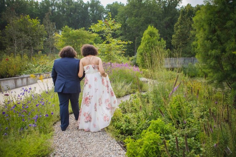 A bride and groom walking down a path at Brookside Gardens in Wheaton, Maryland.