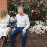 In Downtown Annapolis, a family poses for a portrait on a brick wall surrounded by flowers.