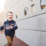 A young boy, part of a loving family, running down a sidewalk in downtown Annapolis with a smile on his face.