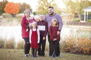 A family posing in front of a serene pond at sunset while capturing beautiful family portraits.