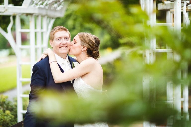 A bride and groom kissing in front of a gazebo at Quiet Waters Park in Annapolis, Maryland.