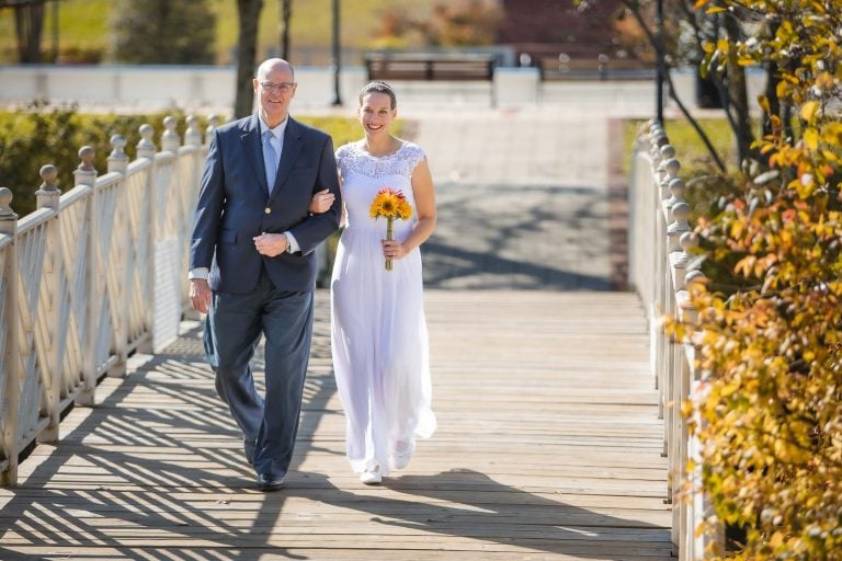 A bride and her father walking on a bridge at Quiet Waters Park in Maryland.