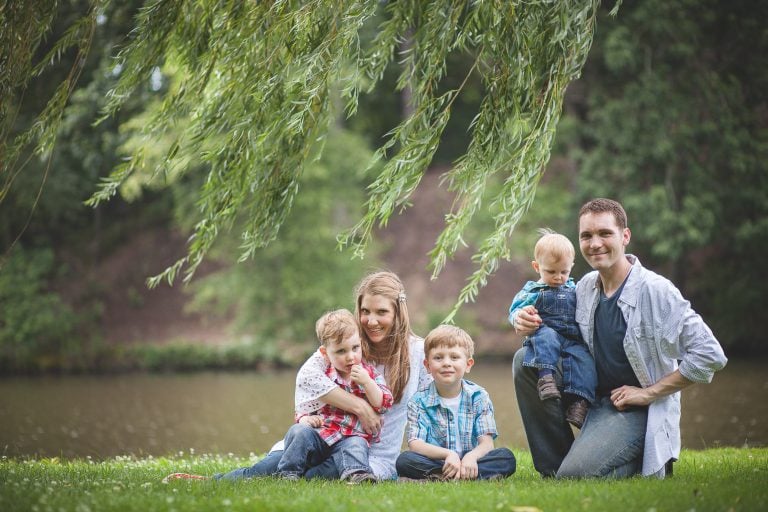 A family sits on the grass under a willow tree at Allen Pond in Bowie, Maryland.