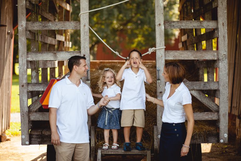 A family is standing in front of a barn at Agricultural History Farm Park in Derwood, Maryland.