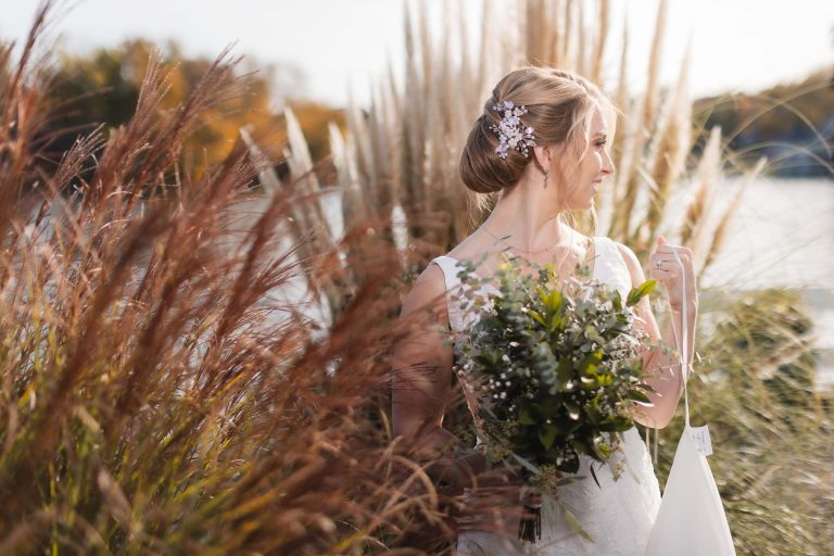 A bride in a wedding dress standing in front of tall grass at Anchor Inn.