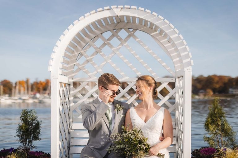 A bride and groom sitting in a white wicker chair at Anchor Inn in Annapolis.