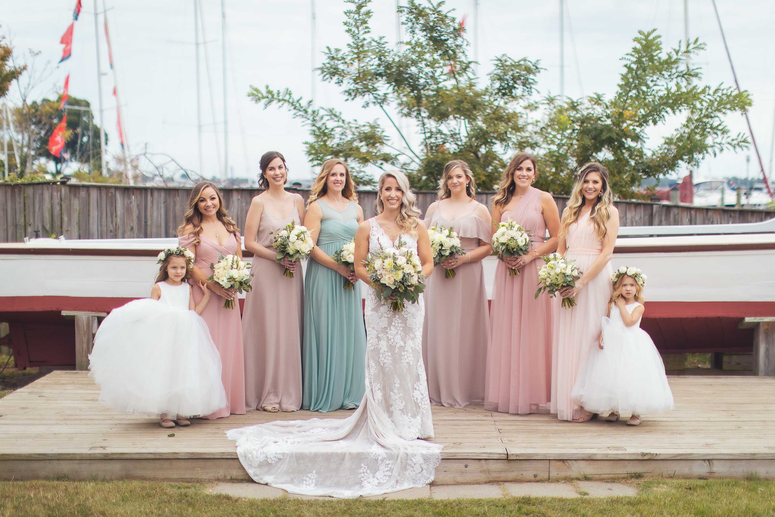 A bride and her bridesmaids pose in front of a boat at Annapolis Maritime Museum in Maryland.