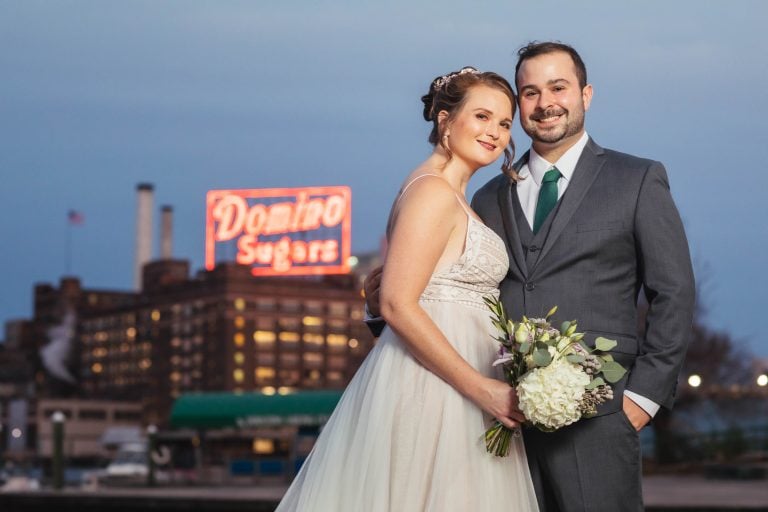 A bride and groom pose for a photo in front of the Baltimore Museum of Industry in Maryland.