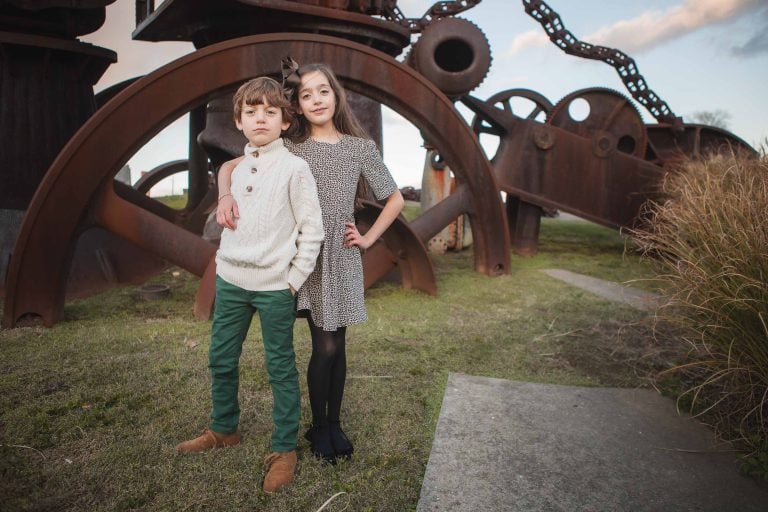 Two children standing in front of a large metal structure at the Baltimore Museum of Industry in Maryland.