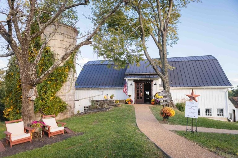 A white barn in Hamilton, Virginia surrounded by chairs and a tree.