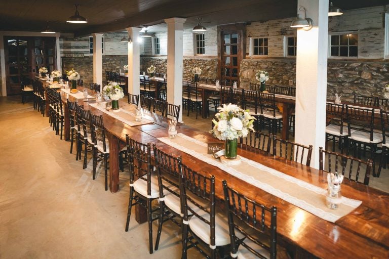 A long table is set up in a room with a stone wall at the Barns at Hamilton Station Vineyards in Virginia.