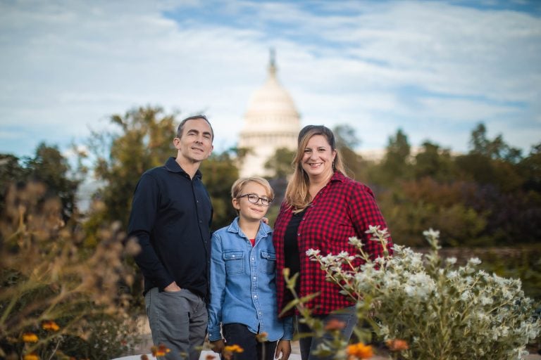 A family posing in front of the Bartholdi Fountain & Gardens with the United States Capitol in the background in Washington DC.