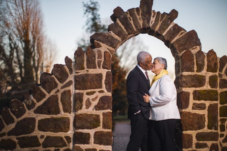 An older couple kissing in front of Belair Mansion.