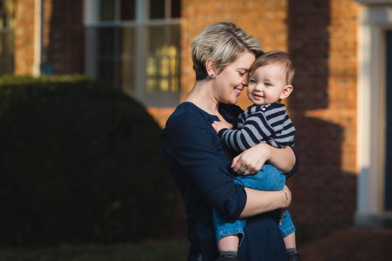 A woman holding a baby in front of Belair Mansion in Bowie, Maryland.