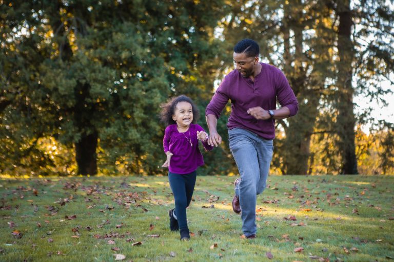 A father and daughter running in Belair Mansion Park.