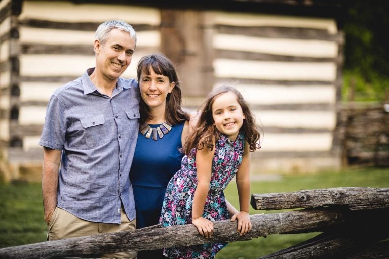 A family poses in front of a log cabin in Maryland.