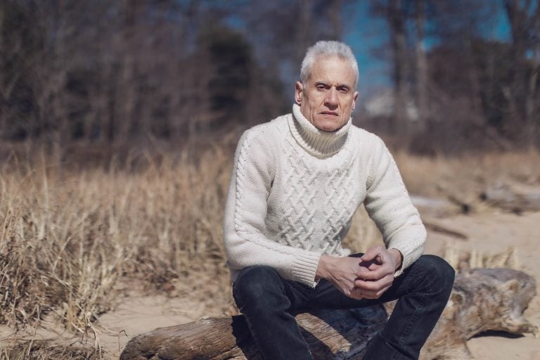 An older man sitting on a log at Beverly Triton Nature Park in Maryland.