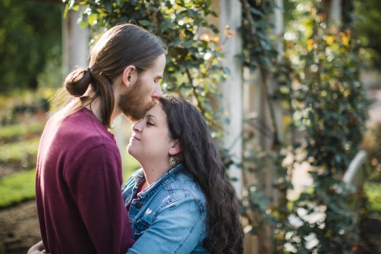 A couple kisses in front of the Bonair Rose Garden in Virginia.