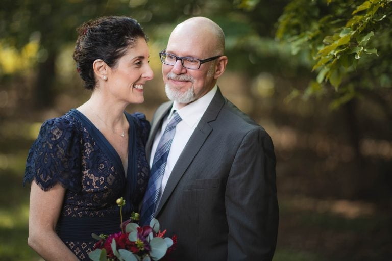 A man and woman smiling in front of the Dorsey Chapel in Glenn Dale, Maryland.