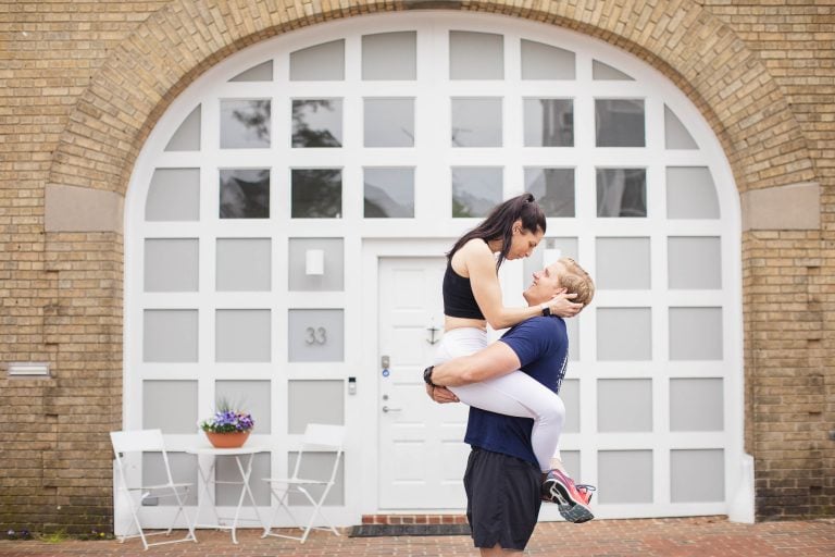 A man carries a woman in front of a brick building in Downtown Annapolis, Maryland.