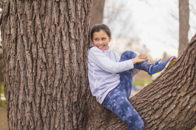 A young girl sitting on a tree in General Getty Neighborhood Park.