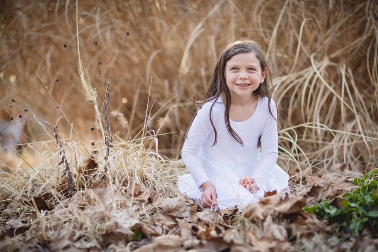 A little girl in a white dress sitting in Glen Echo Park.