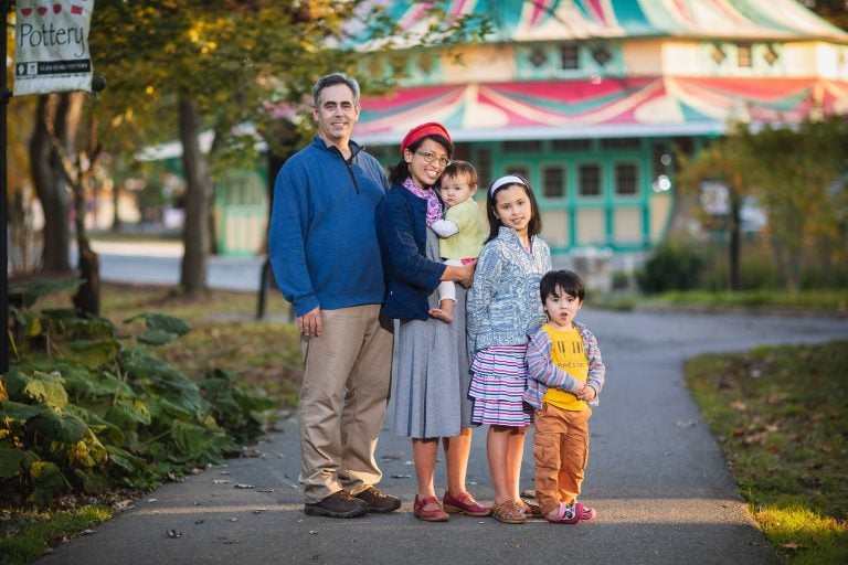 A family poses for a photo in front of the carousel at Glen Echo Park.