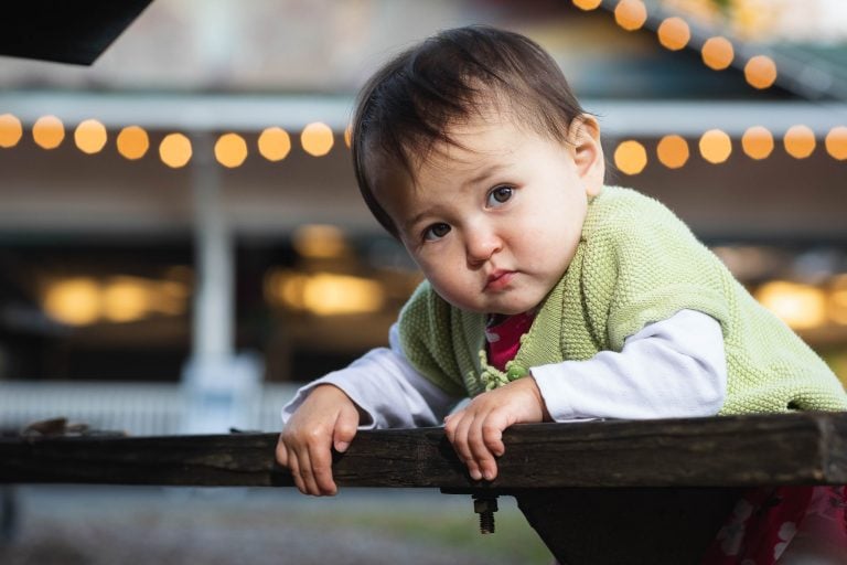 A baby is leaning over a picnic table at Glen Echo Park in Maryland.