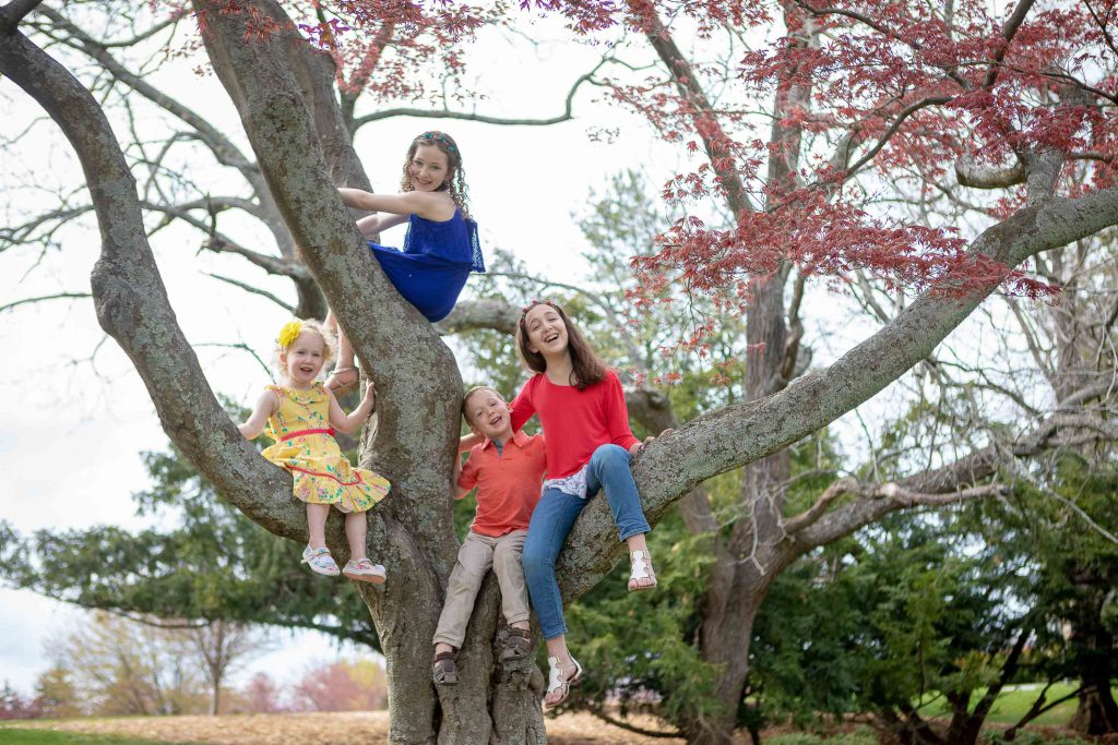 A family sits on the branches of a tree at Glenview Mansion in Rockville, Maryland.